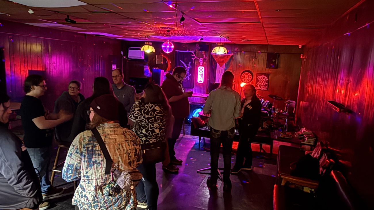 A neon-lit bar full of people at a Join Dayton meetup